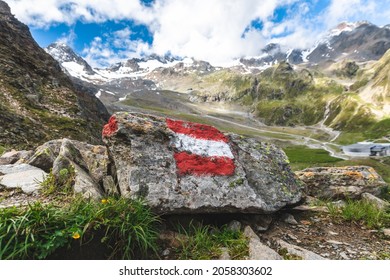 Alpine hiking trail in Austria, marked with a painted Austrian flag on a rock along the route. This painted rock is located in the Valley of Stubai, in the Austrian Tyrol.