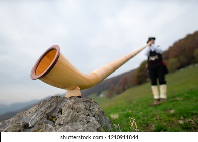 Alpine Horn. A Man Plays In An Alpine Valley.