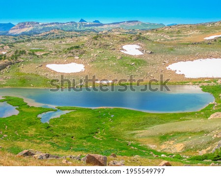 Alpine lake at Beartooth Pass on Beartooth Highway. Beartooth Mountains, Wyoming, United States. Scenic aerial landscape in summer season. Blue sky with copy space.