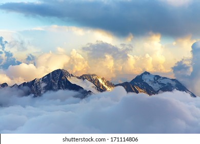 alpine landscape with peaks covered by snow and clouds - Shutterstock ID 171114806