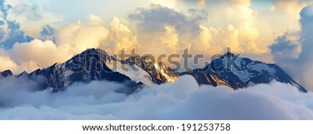 alpine landscape with peaks covered by snow and clouds. banner. panorama