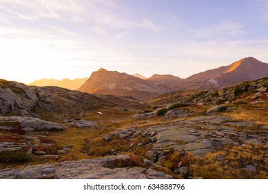 Alpine meadow and pasture set amid high altitude mountain range at sunsets. The Italian Alps, famous travel destination in summertime. - Powered by Shutterstock