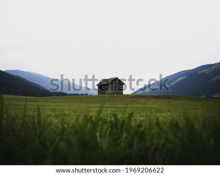 Alpine mountain panorama of idyllic remote wooden shed cabin in green grass field meadow of Dolomites alps South Tyrol Italy Europe