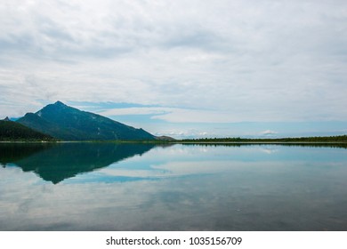 Alpine Mountains and Cloudy Sky with Reflections in Lake