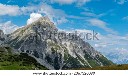 Alpine peak on sunny summer day, blue sky with white clouds in background. Serles peak 2,718 m, Stubai Alps, Tyrol, Austria.
