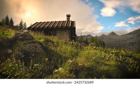 Alpine picturesque village high in the Alps mountains. Golden Sunset on the hillside. A golden sunset with colorful sky, trees, and clouds.