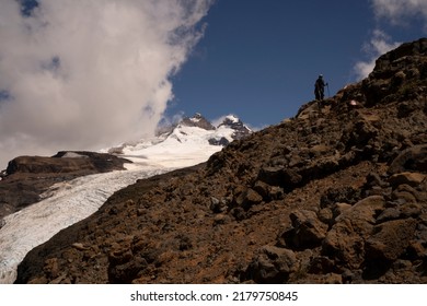 Alpine scenic. View of two hikers climbing up Tronador hill and glacier Castaño Overo in the Andes mountains in Patagonia Argentina. The rocky mountaintop and glacier ice field in a sunny day.