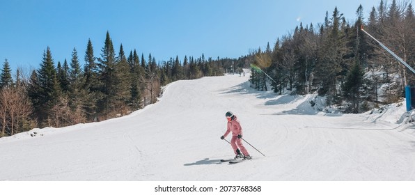 Alpine ski. Skiing woman skier going dowhill against snow covered trees background in winter Woman in red ski jacket. Mont Tremblant, Quebec, Canada