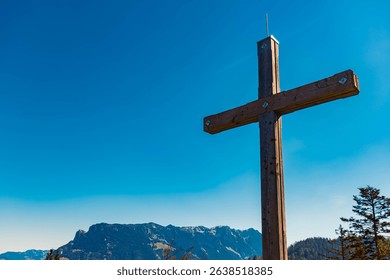Alpine spring view with a summit cross and Mount Zahmer Kaiser in the background at Kaiserlift Kufstein, Tyrol, Austria
