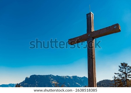 Alpine spring view with a summit cross and Mount Zahmer Kaiser in the background at Kaiserlift Kufstein, Tyrol, Austria