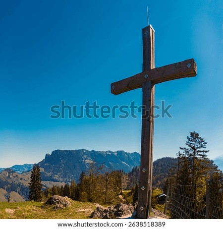 Alpine spring view with a summit cross and Mount Zahmer Kaiser in the background at Kaiserlift Kufstein, Tyrol, Austria
