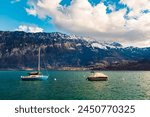 Alpine view on a cloudy spring day with boats on Lake Thunersee near Merligen, Sigriswil, Bern, Switzerland