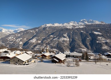  alpine village with snowy roofs in tarentaise valley view on snowcapped mountains under blue sky 