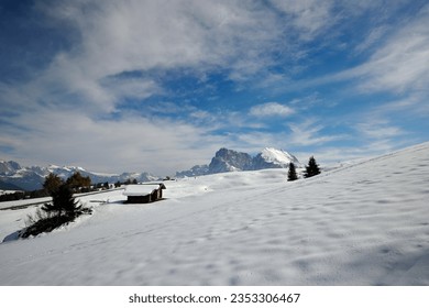 An Alpine winter landscape with mountain huts, Dolomites peaks in winter, Wintry Dolomites panorama,Snow-capped mountains with a blue sky , Cozy and rustic mountain huts in winter,  - Powered by Shutterstock