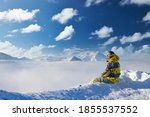 Alpine winter mountain landscape with man sitting above low clouds. French Alps covered with snow in sunny day. Val-d