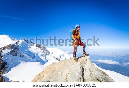 Alpinist guy mountaineer man standing posing Mont Blanc du Tacul snow mountain summit. Chamonix valley view beautiful landscape, Europe France Alps range tourism.