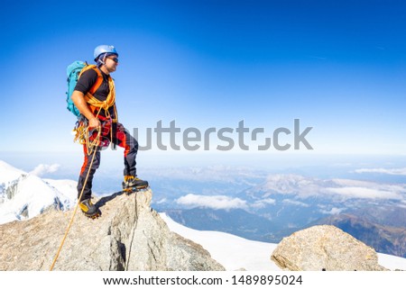 Alpinist guy mountaineer man standing posing Mont Blanc du Tacul snow mountain summit. Chamonix valley view beautiful landscape, Europe France Alps range tourism.