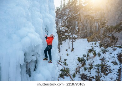 Alpinist Man With Ice Climbing Equipment On A Frozen Waterfall