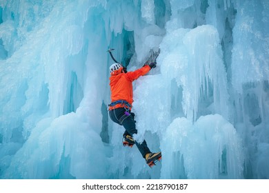 Alpinist Man With Ice Climbing Equipment On A Frozen Waterfall