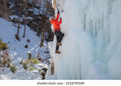 Alpinist Man With Ice Climbing Equipment On A Frozen Waterfall