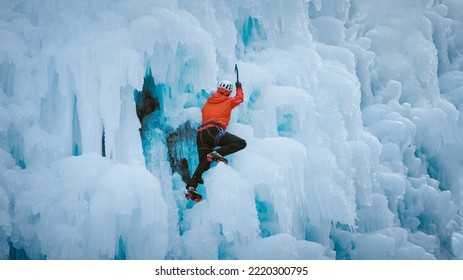 Alpinist Man With Ice Climbing Equipment On A Frozen Waterfall