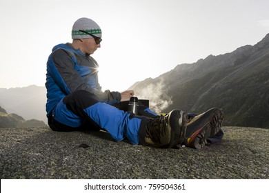 Alpinist pauses and prepares a warm drink, Switzerland