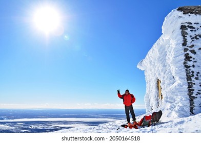 Alpinist standing near forsaken ski lift station with travel backpacks in front of huge snow capped landscapes in Khibiny, Russian Federation - Shutterstock ID 2050164518