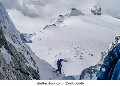 Alpinst rappeling down from a mountain. WInter alpine climbing on snow and rock. Abseiling on rope on a glacier, Mont Blanc Massif, France.