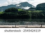 Alpnachersee mountain lake - view from the boardwalk along the northern bank. Clouds covering Stanserhorn alpine peak behind the waters of Alpnachersee. 