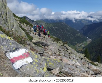 Alps, Switzerland - circa July 2016: Silhouettes of hiking tourists on the route from the Col de la Forclaz pass to the Col de Balme. Tourist marking of trail on rock. Tour du Mont Blanc