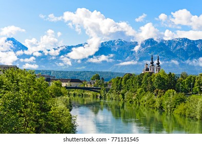 The Alps in Villach - mountain range in the clouds with a small chapel on the bank of the river