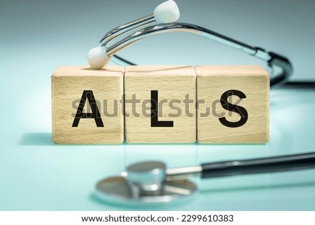 ALS or Written on wooden blocks, Amyotrophic lateral sclerosis, a rare nervous system disease affecting the motor nerves in the cortex and brainstem and spinal cord, loss of muscle control, close up