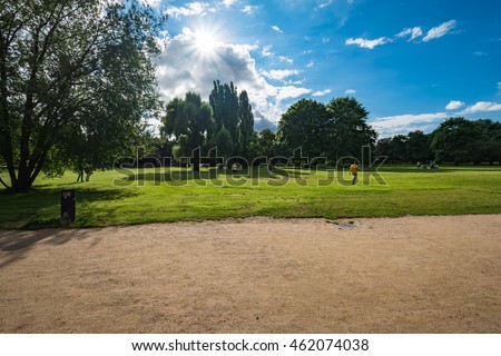 Alster Park in Hamburg Germany on a summer day. 
People playing outdoor mobile game on smart phones, catching virtual pocket monsters outside in city on a sunny day, colorful image for business, blogs