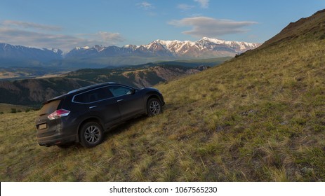 Altai Krai, Russia - July 15, 2015: Crossover Nissan X-TRAIL on the hillside in the Kurai steppe against the backdrop of the North Chuy ridge at dawn.