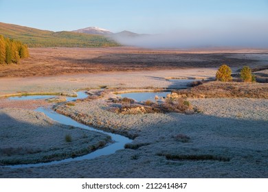 Altai river Kurkurek on Eshtykel plateau covered with morning fog. Autumn, trees are in fall yellow colors, grass under hoarfrost.  Altai, Siberia, Russia