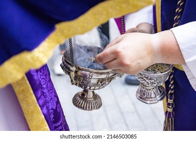 An Altar Boy Or Acolyte In A Holy Week Procession Filling One Of The Censors With Incense. Selective Focus Photography With Focus In The Border Of The Censer Only