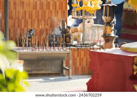 Altar with many smoking aroma incense sticks in front of small elephant statues. Burning incense sticks outdoors at temple. Offering for the deities at Thailand. Blurred foreground