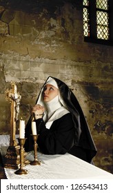 Altar of a medieval 17th century church and a young nun in prayer