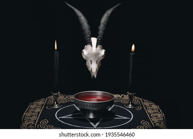 Altar For Satanic Rituals. Witchcraft Composition With Goat Skull, Pentagram Cloth, Candles And Ritual Bowl With Blood. Occult And Esoteric Concept.
