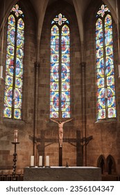 Alter with candles, Jesus on the cross and stained glass windows under high beautiful vaulted ceiling inside the church. - Shutterstock ID 2356104347