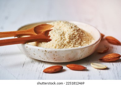 Alternative almond flour. Grated crushed almonds, chopped in a blender, plate, spoon, nuts on the table. White background, side view, close up - Shutterstock ID 2251812469