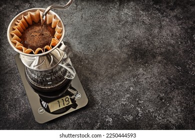 Alternative Coffee Brewing. Dripping Water From Gooseneck Kettle Into Coffee Dripper Filter Holder With Coffee Ground. Cup Pour Over Coffee Maker Standing On Digital Scales 
