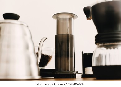 Alternative coffee brewing method set. Stylish accessories and items for alternative coffee on wooden table. Aeropress, steel kettle, electronic scales, manual grinder, coffee beans, filters