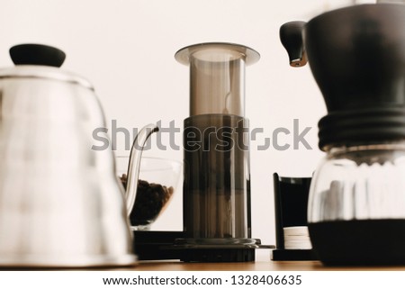 Alternative coffee brewing method set. Stylish accessories and items for alternative coffee on wooden table. Aeropress, steel kettle, electronic scales, manual grinder, coffee beans, filters