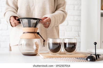Alternative coffee brewing. woman brewing hot black coffee in glass coffee pot standing at the white table
