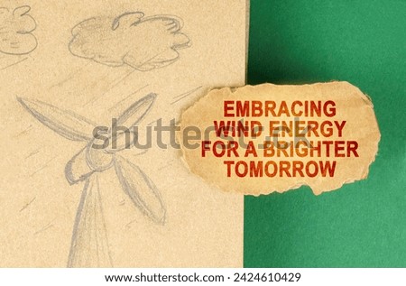 Alternative energy concept. On a green surface there is a drawing with a wind generator and a cardboard with the inscription - Embracing wind energy for a brighter tomorrow