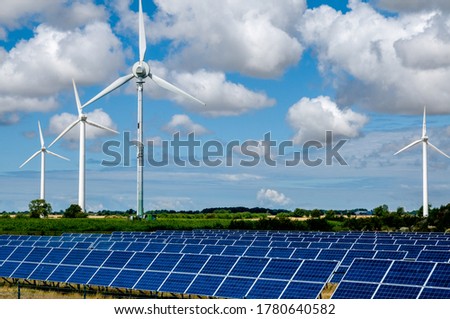 Alternative energy production concept. Wind turbines and solar panels against the backrop of a rural landscape