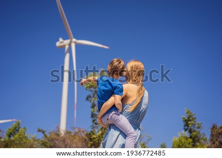 Alternative energy, wind farm and happy time with your family. Happy mother carrying his son on vacation and escape to nature