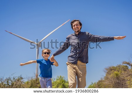 Alternative energy, wind farm and happy time with your family. Happy father on the road with his son on vacation and escape to nature. Father and son waving their arms like a windmill