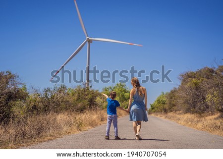 Alternative energy, wind farm and happy time with your family. Happy mother on the road with his son on vacation and escape to nature. Mother and son waving their arms like a windmill